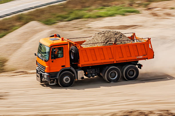 Fast moving orange truck on road making construction site